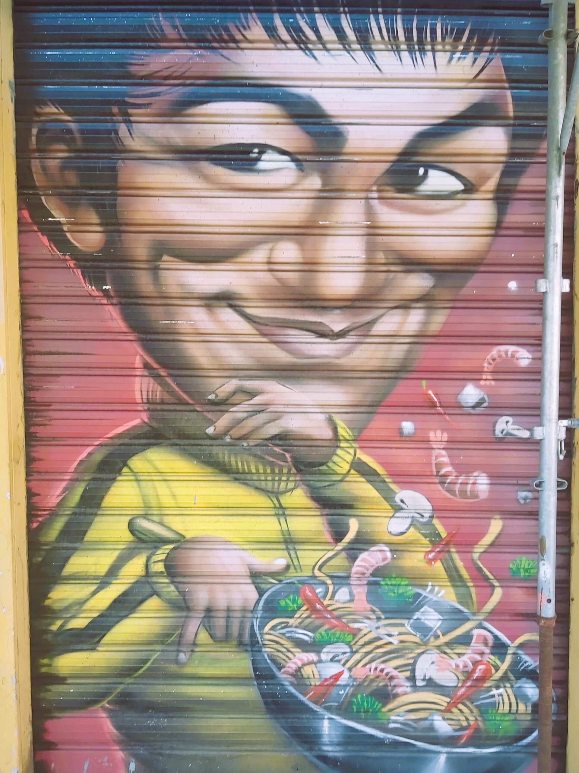 A graffiti image of a man holding a frying pan of noodles in Milan, Italy