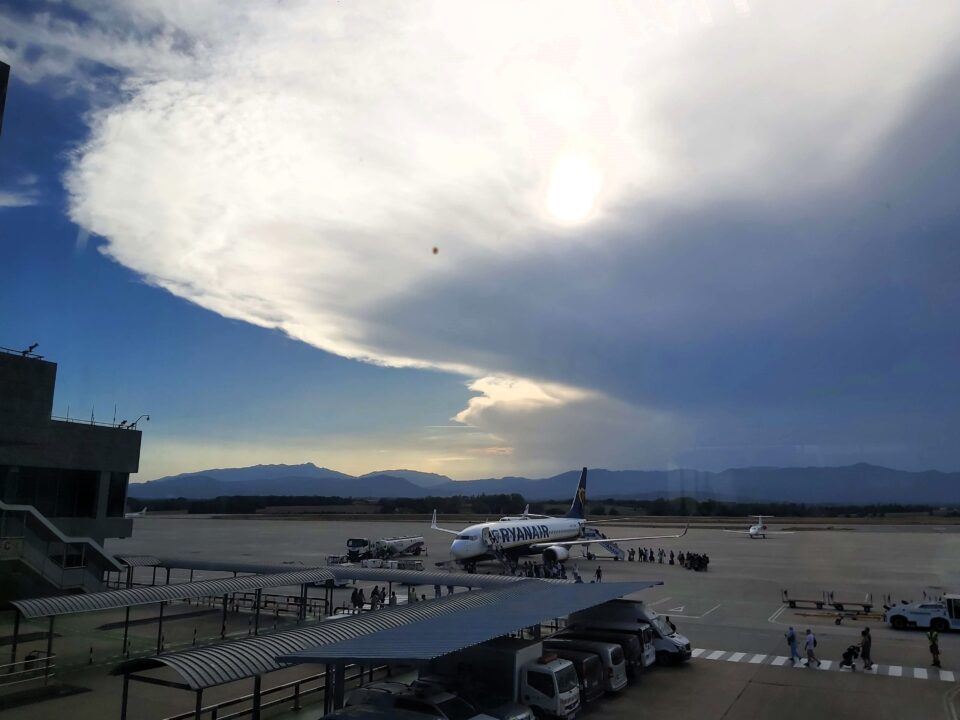 A view from the airport of a Ryanair plane with clouds and mountains in the background