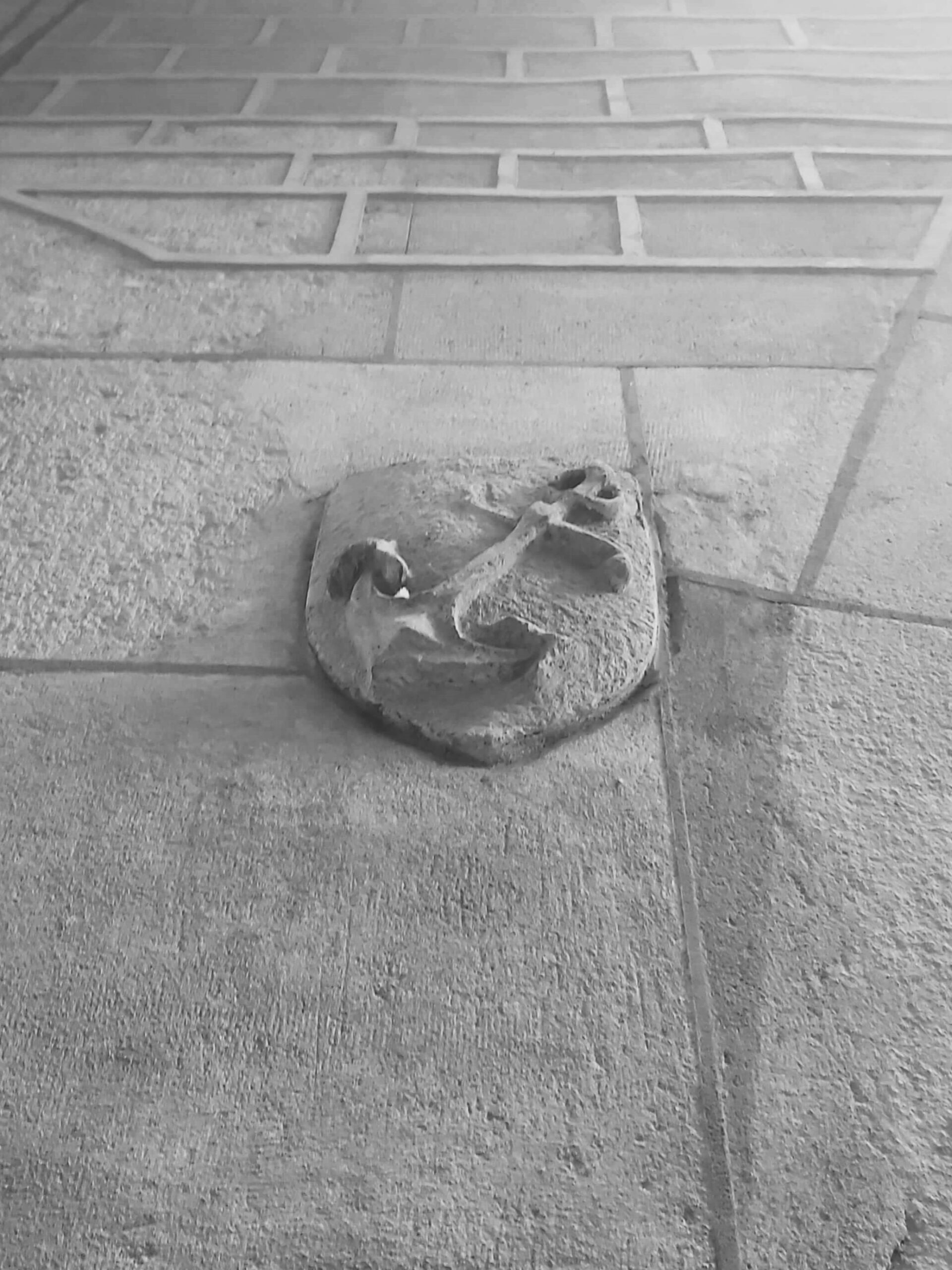 A black and white shot of a carve stone anchor on the side of a building in Barcelona, Spain