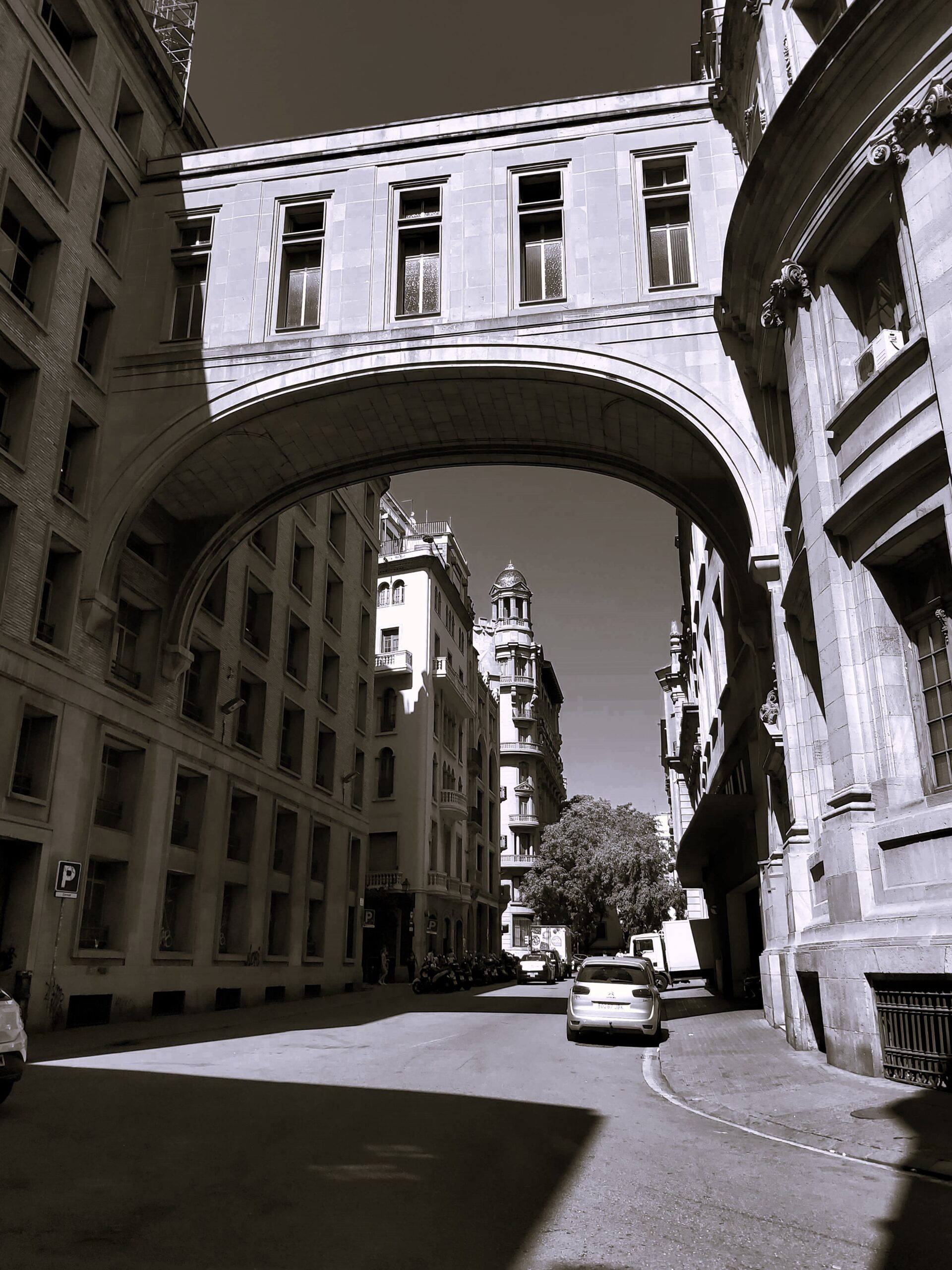 black and white shot of buildings joined by an arched covered walkway in Barcelona, Spain