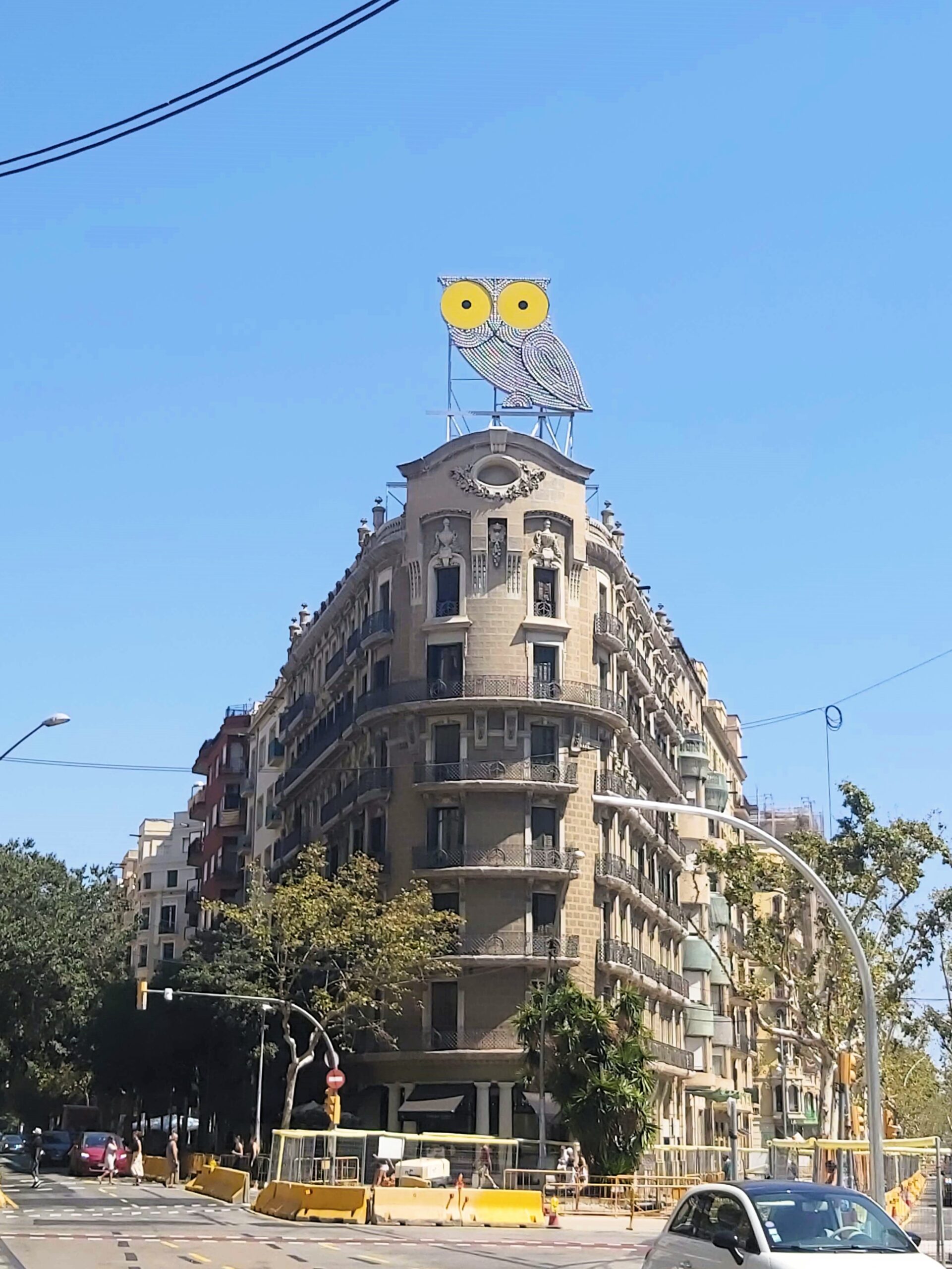 Artwork of an owl with large yellow eyes on top of a building in Spain, Barcelona