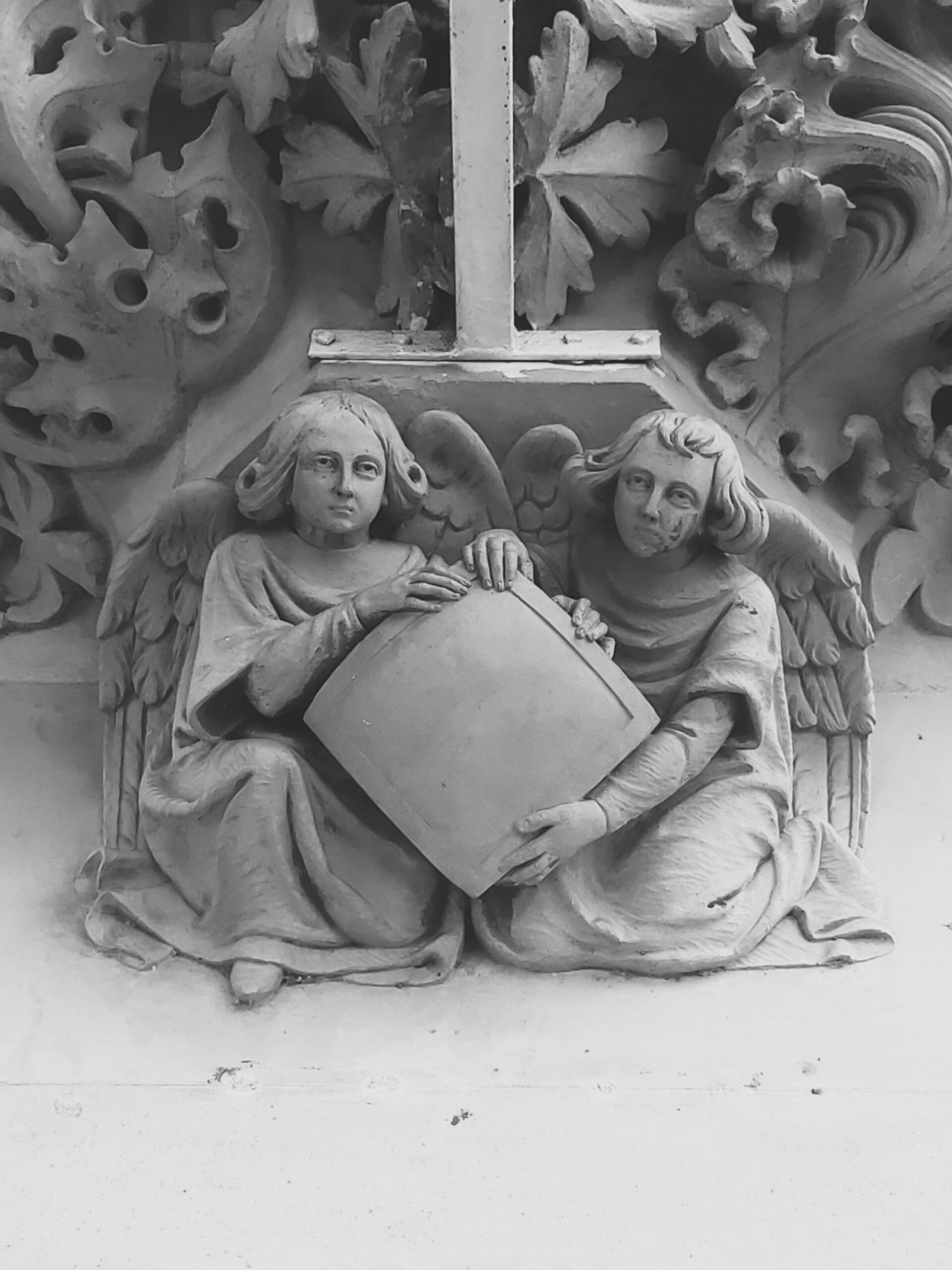 Two angels holding a square, small carving on a building. Barcelona, Spain