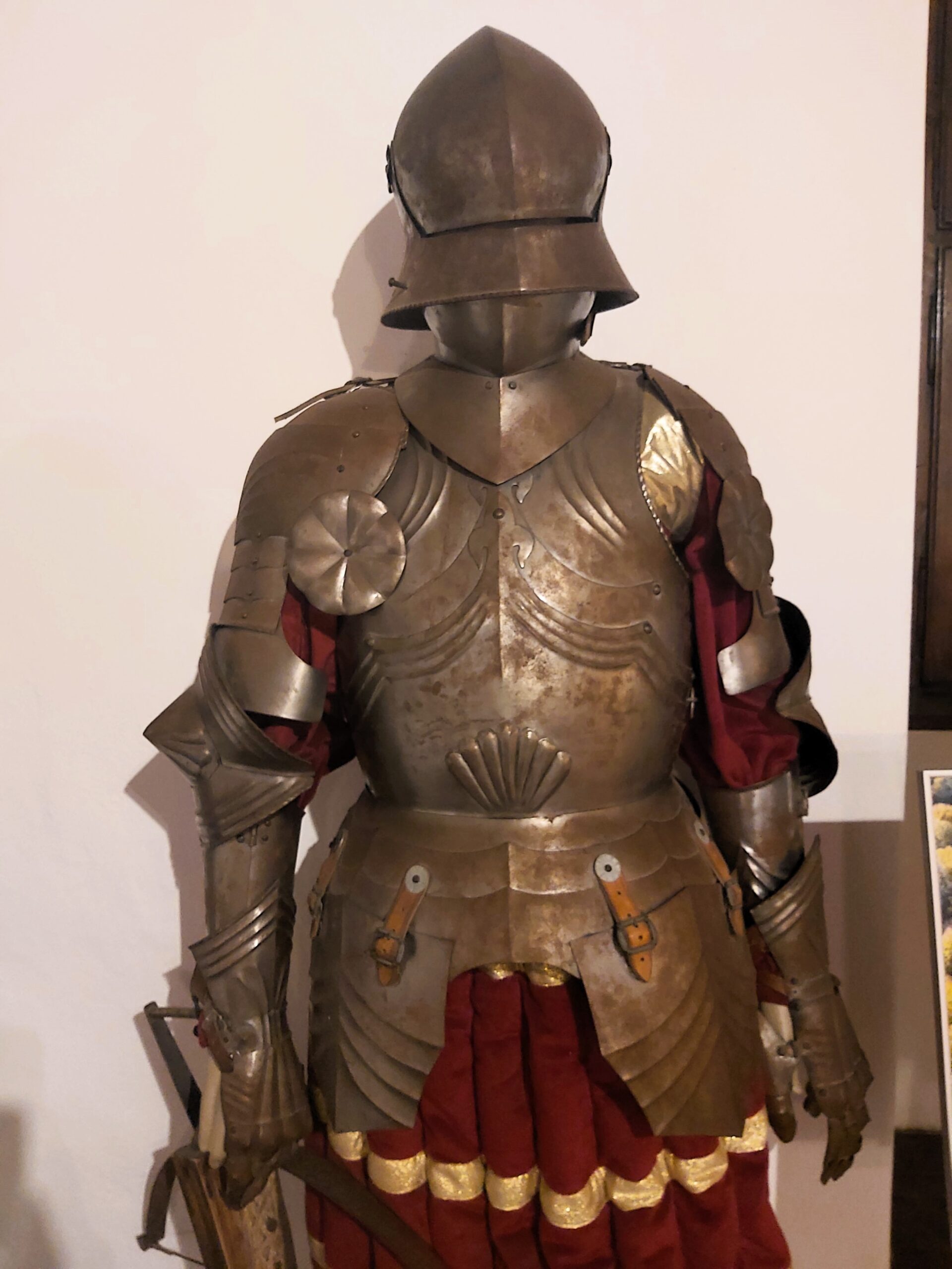 A suit of armour with red and gold cloth underneath in Bran Castle, Romania