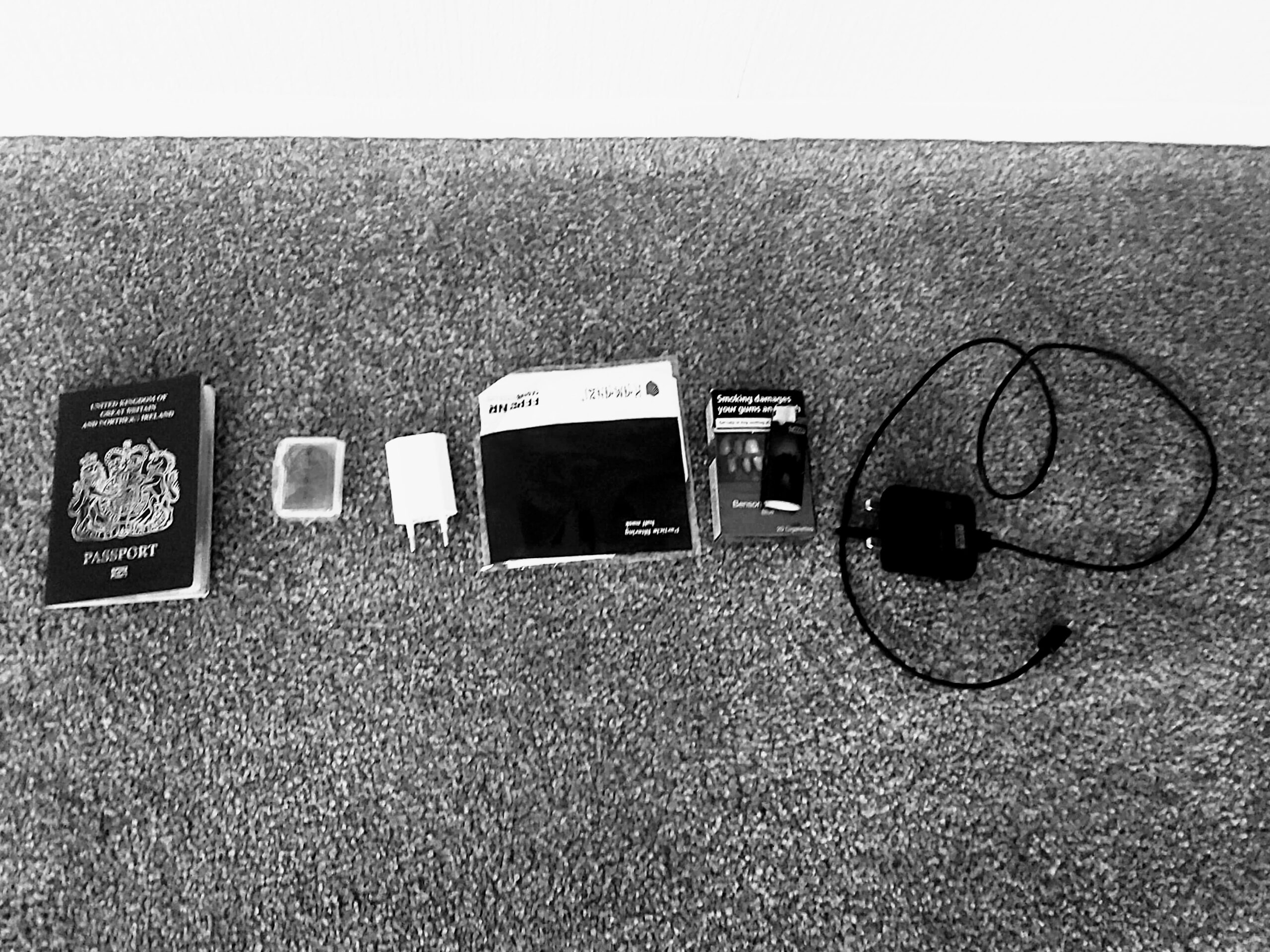 A selection of travel essentials laid out including passport and charger
