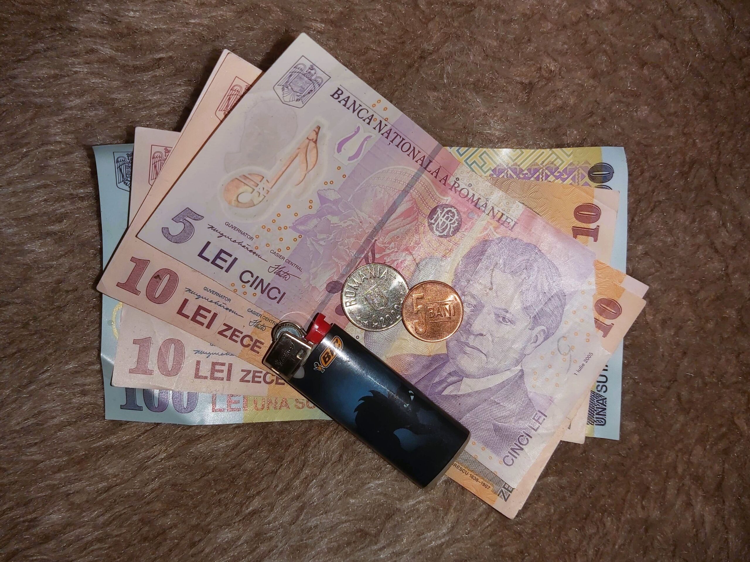 A selection of Romanian currency, with a lighter that has a black cat picture