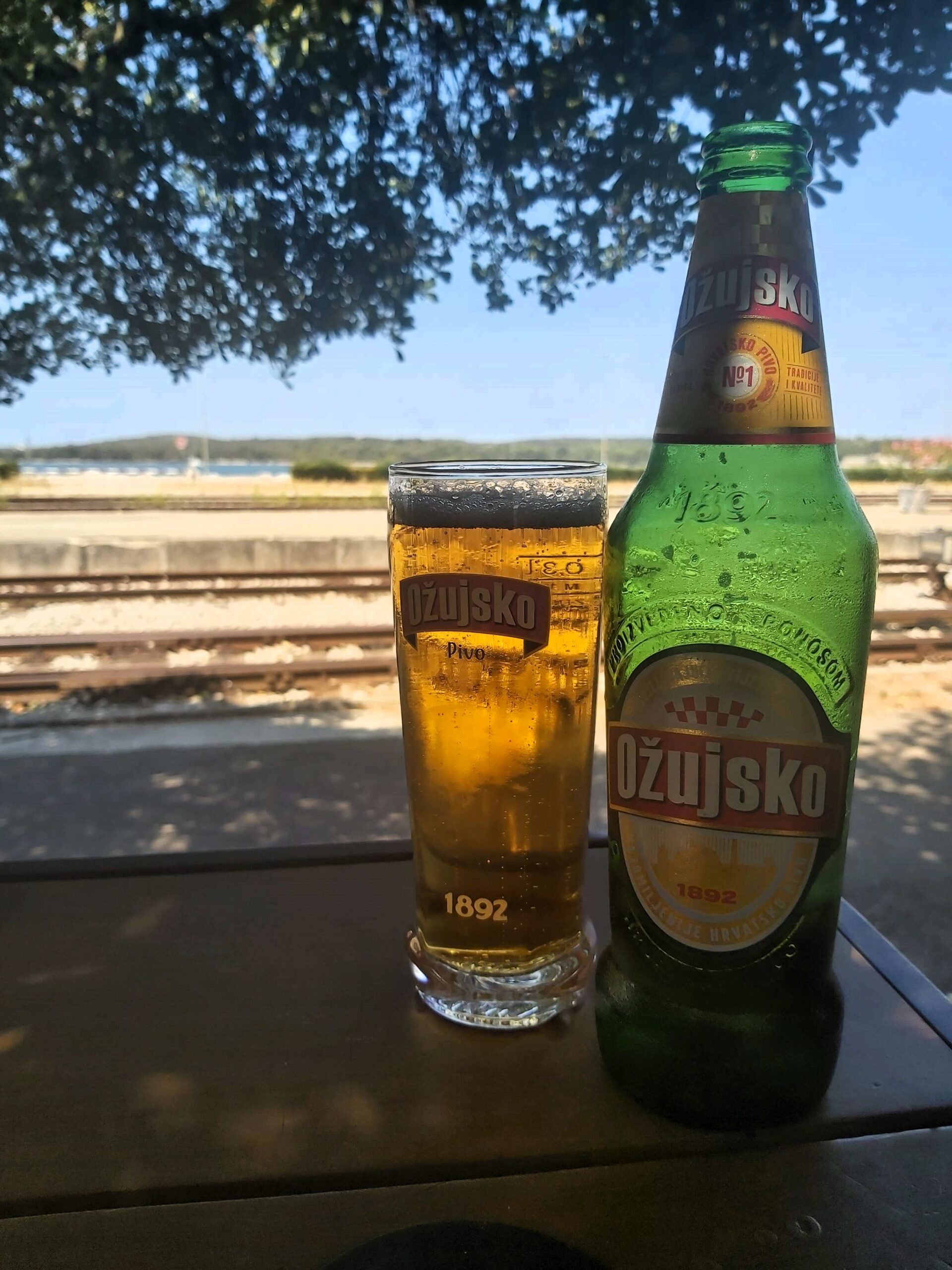 Ozujsko beer with Pula train station platform in background, Croatia