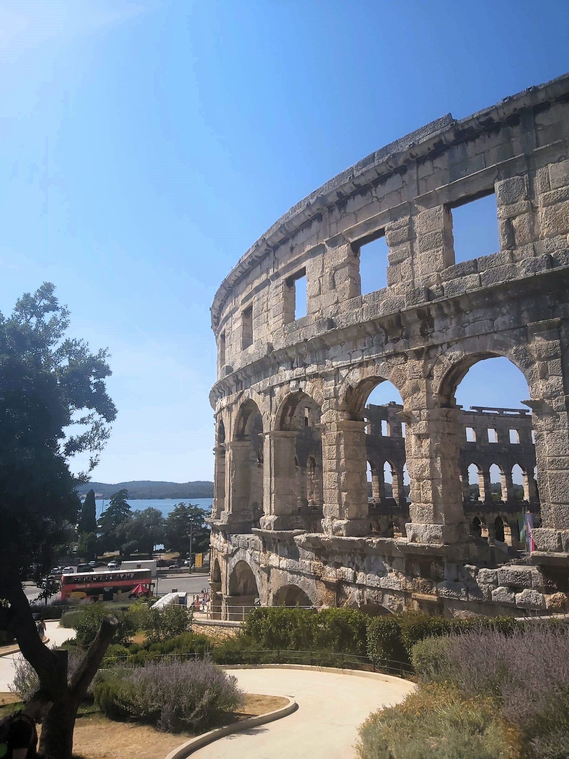 The Roman Amphitheatre with trees and a sea view in the background in Pula, Croatia