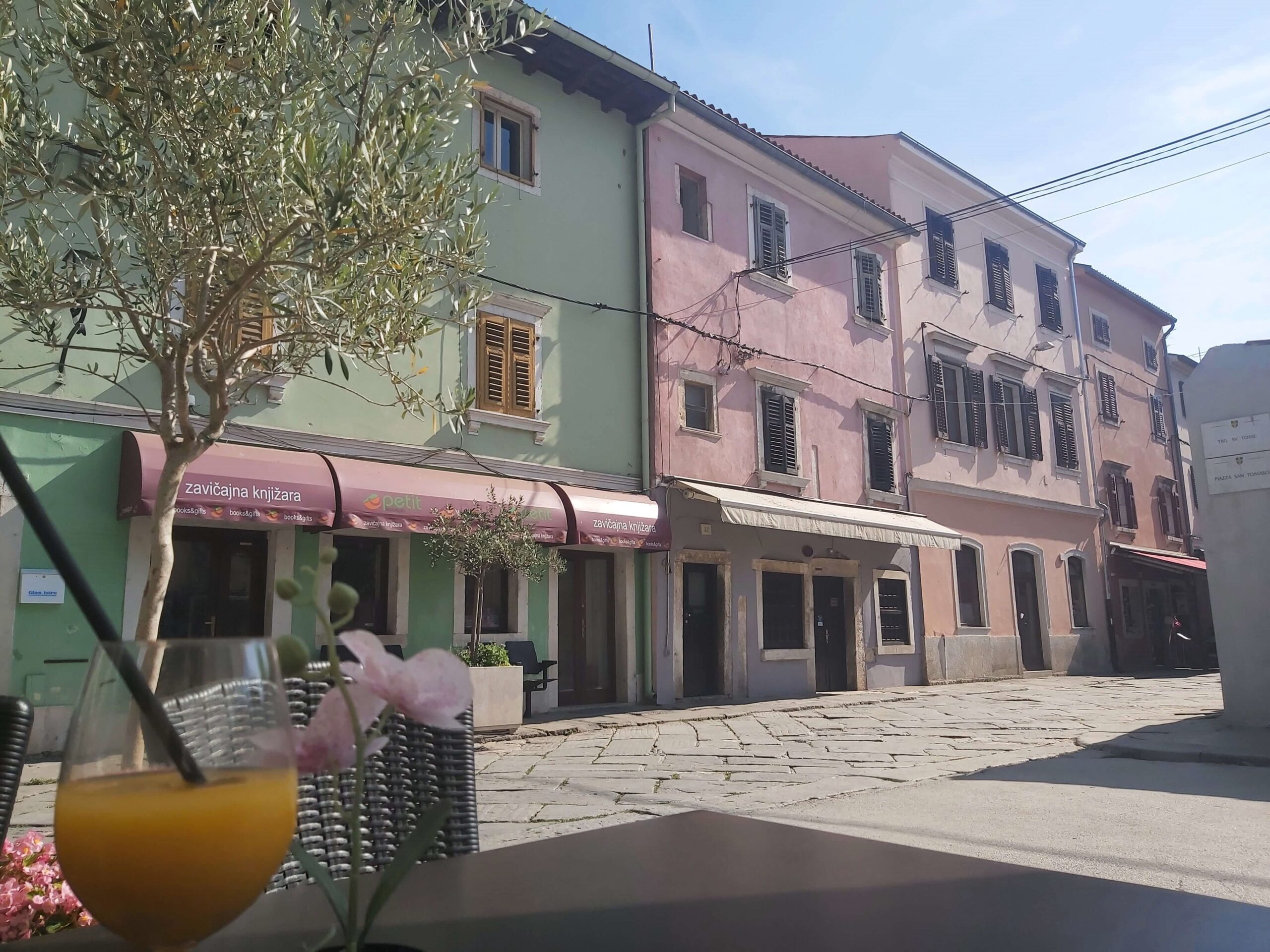 Green and pink buildings dominate a street view in Pula, Croatia