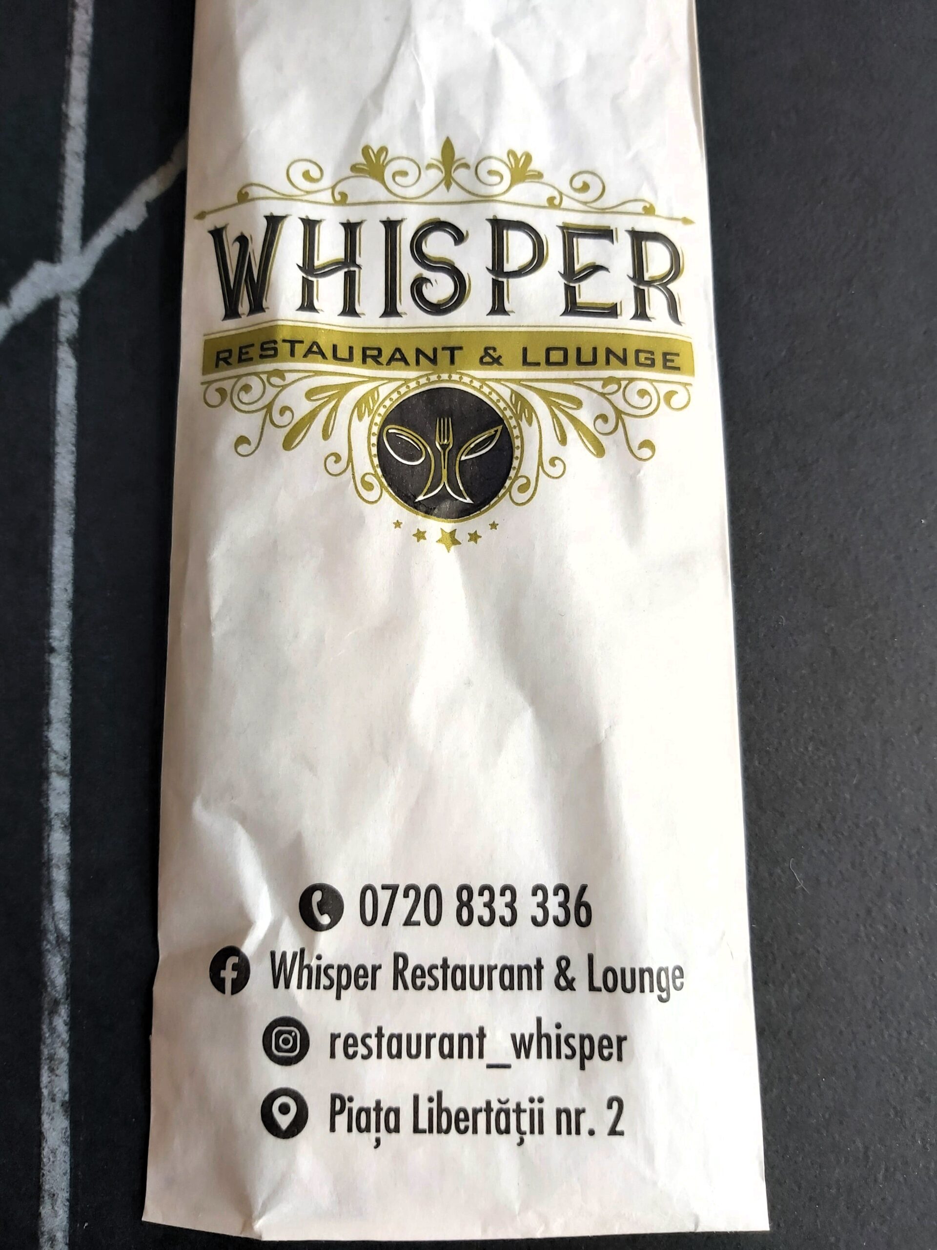 A set of cutlery sheathed with advertising for Whisper Restaurant and Lounge in Timisoara, Romania