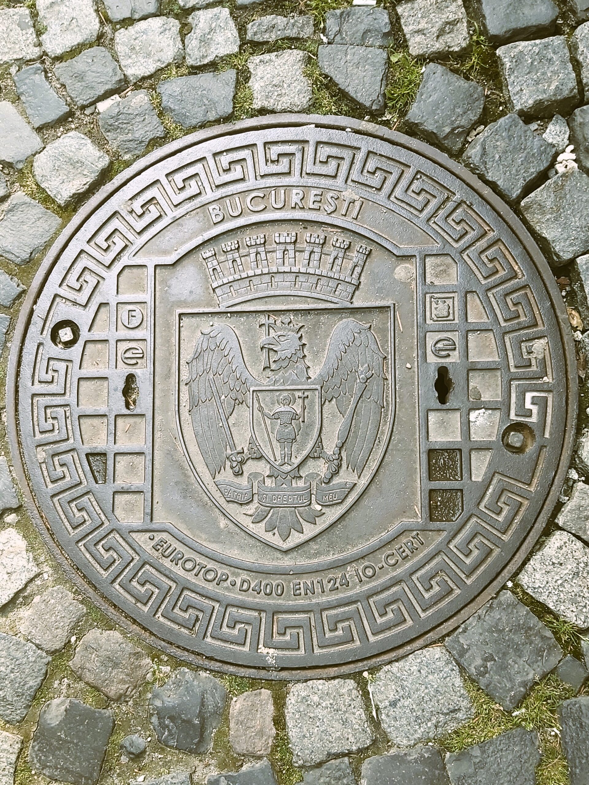 A drain cover with eagle, crown and saint on it in București, Romania