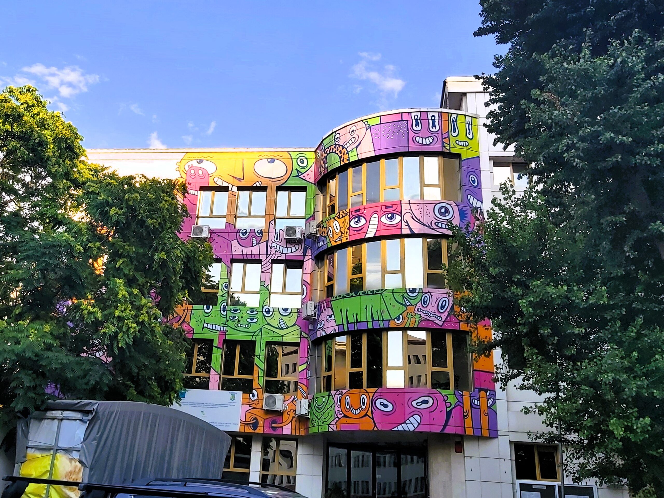 A building with colourful faces painted on it in București, Romania
