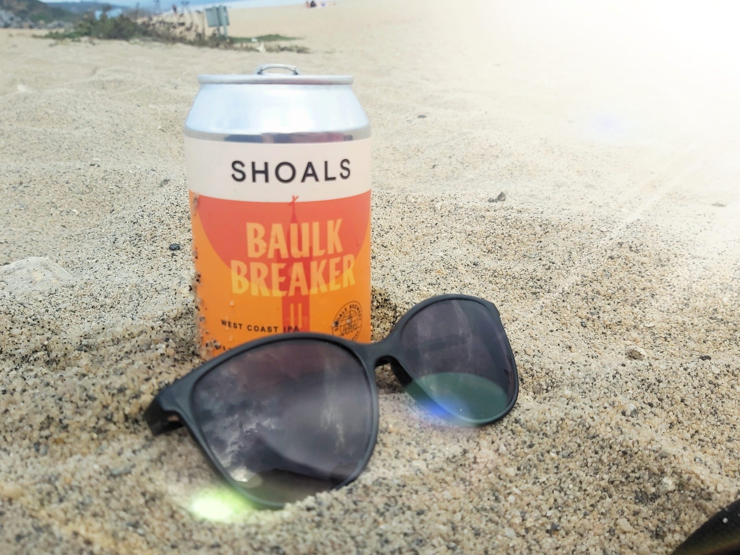 Can of Shoals IPA and sunglasses on the beach at Carlyon bay, Cornwall, England