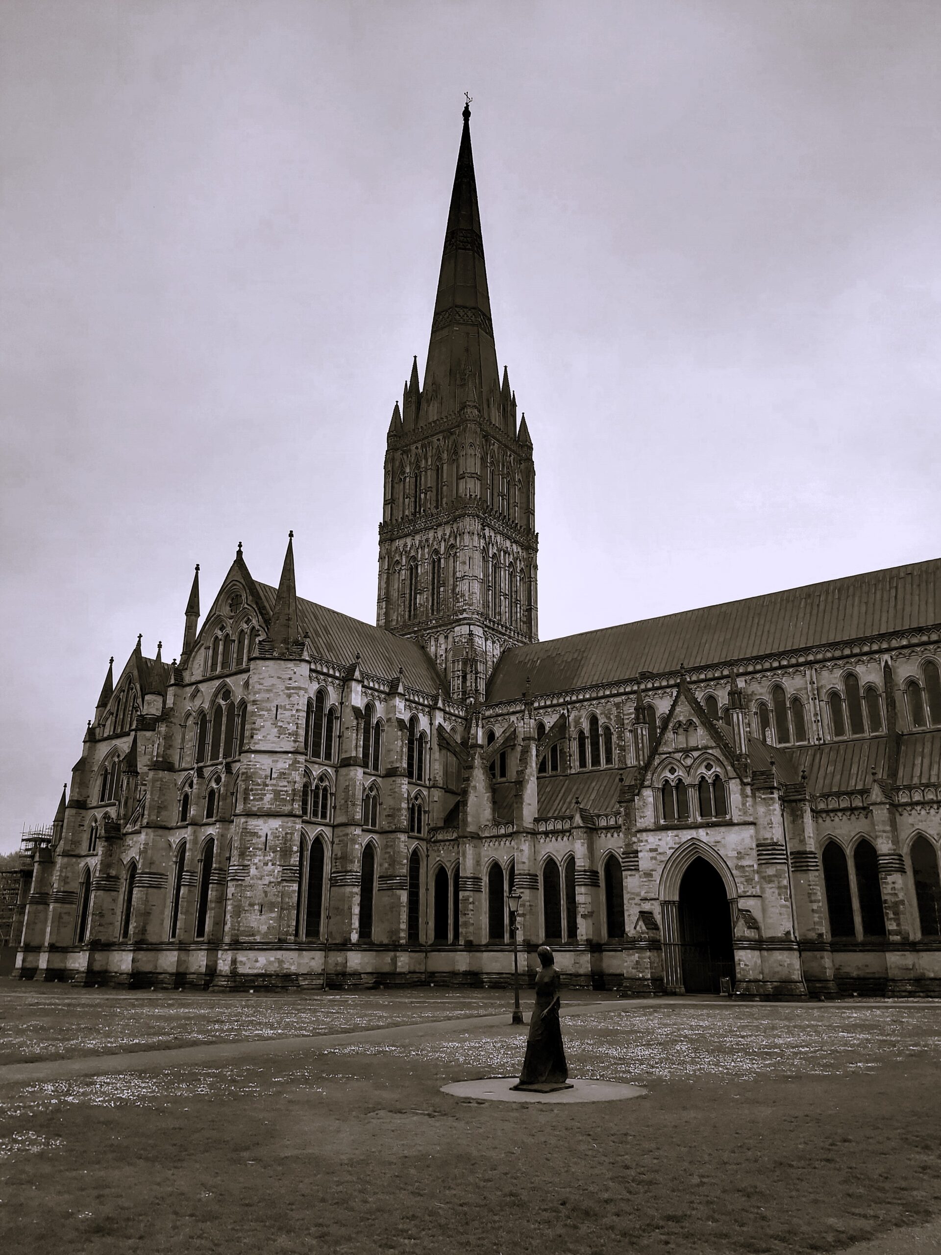 A moody black and white shot with a female tin front of Winchester Cathedral, England