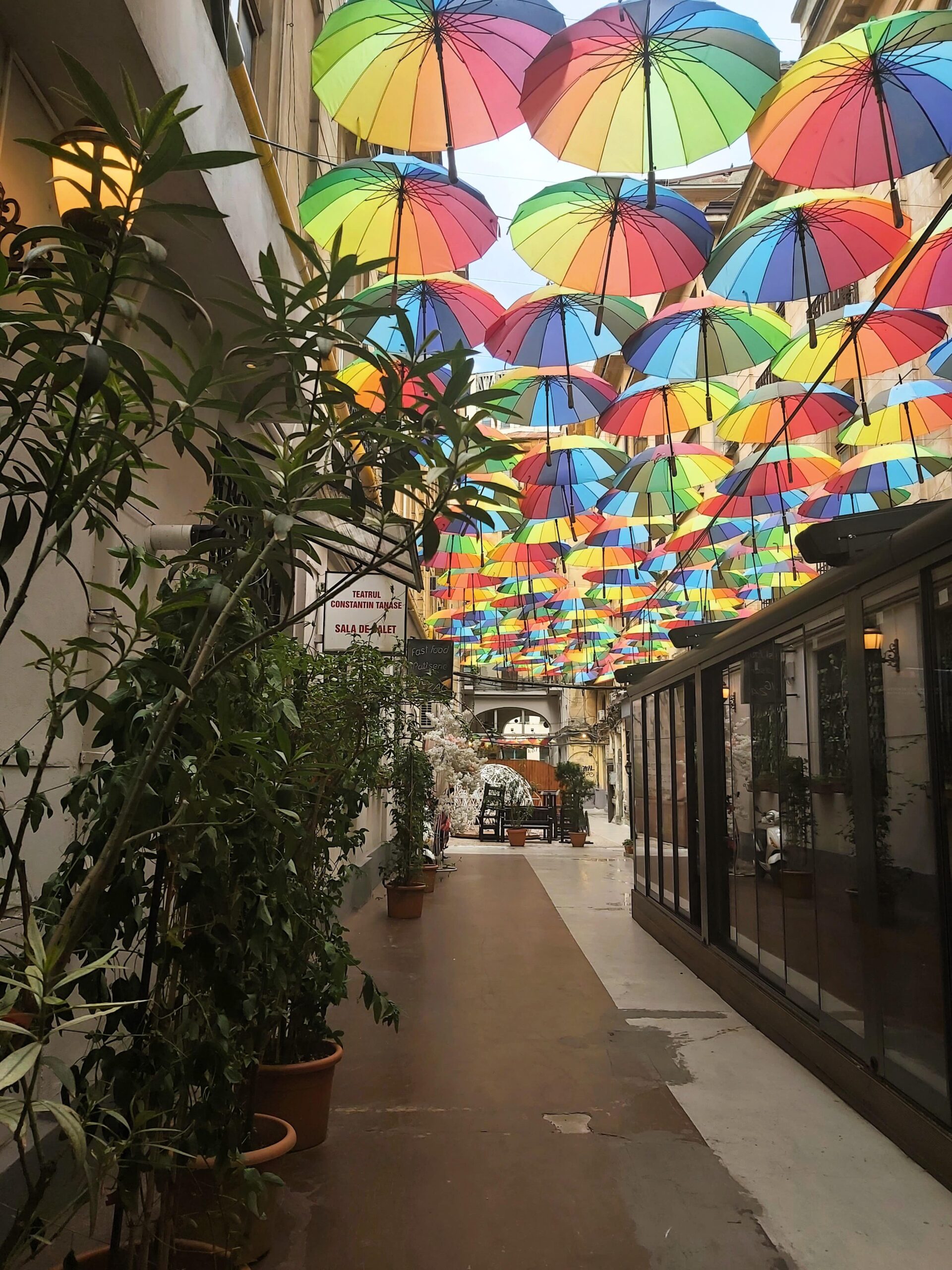 Strada cu Umbrele in București, Romania. A passage with multi-coloured umbrellas hanging above it.