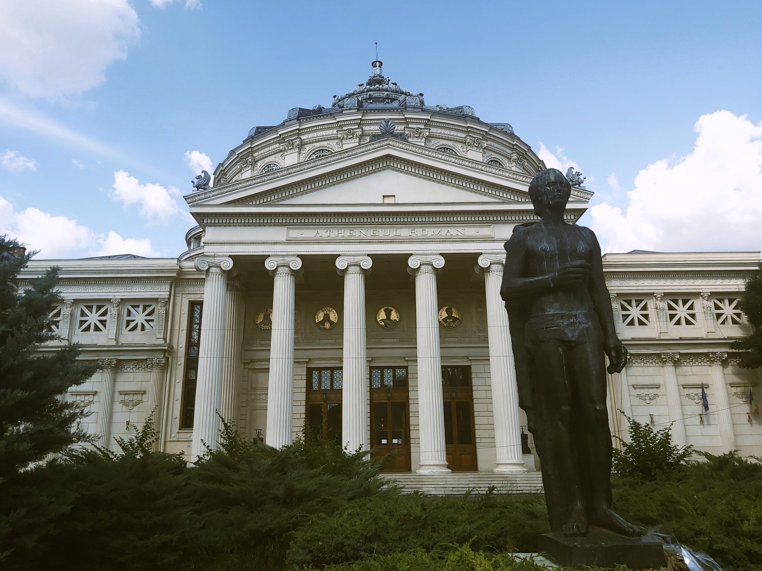 The Ateneul Român (the Romanian Athenaeum) with a statue of Mihai Eminescu in front in București, Romania
