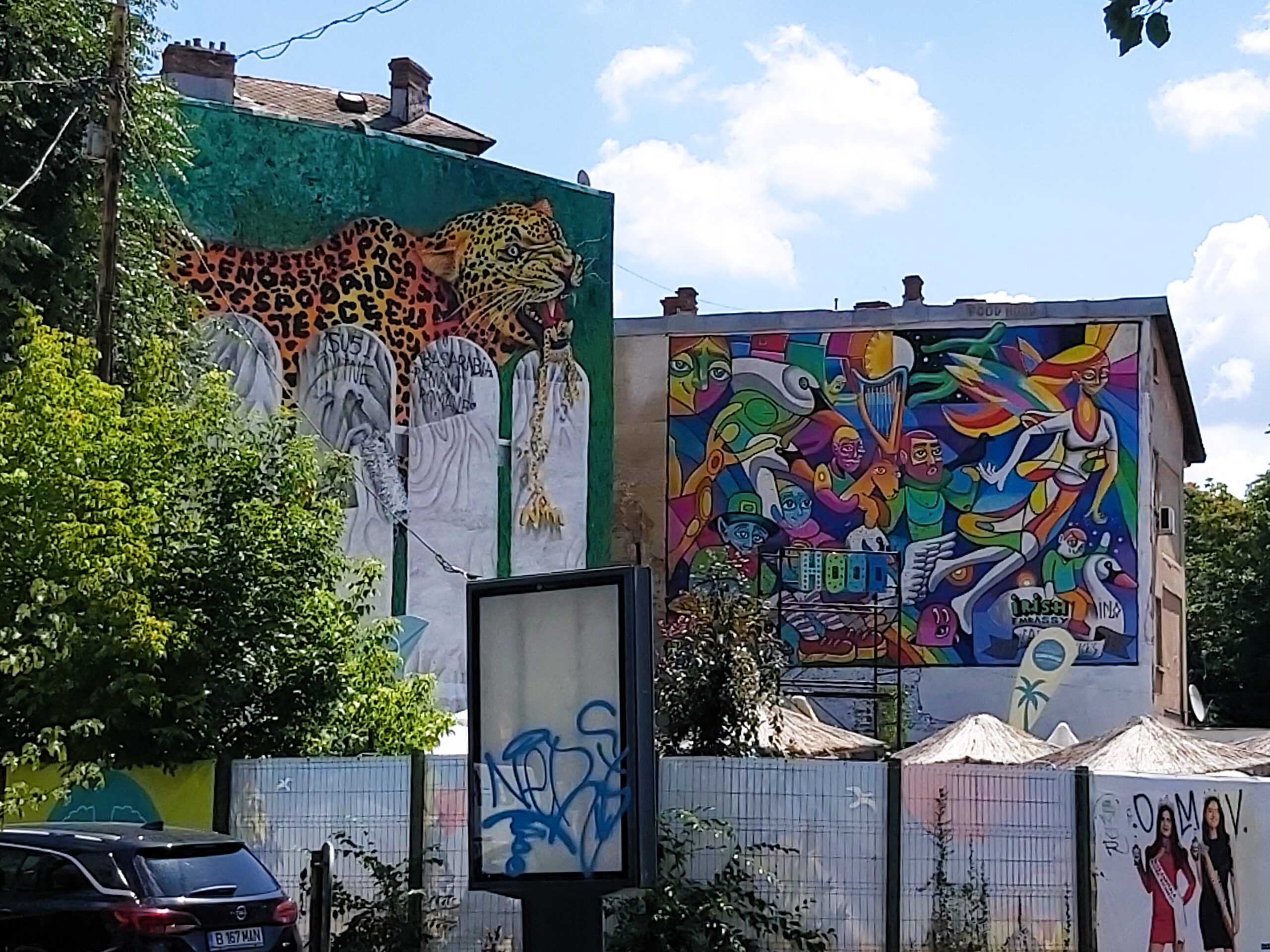 A colourful mural on two buildings consisting of people, swans and a leopard in București, Romania