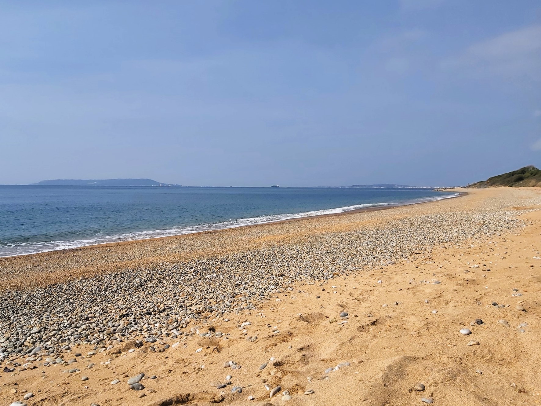 A beach view with a boat in the distance at Ringstead beach, Dorset, England