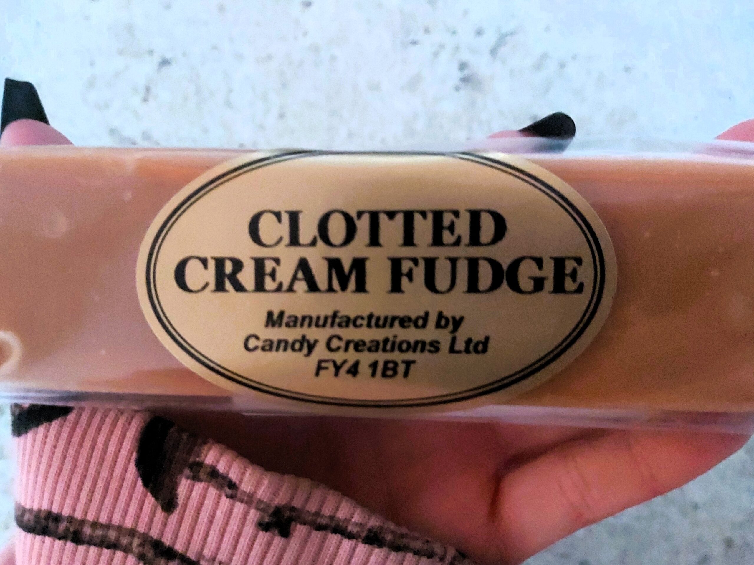 Wandering Lewis, with long black nails, holds clotted cream fudge, bought in Hastings, England