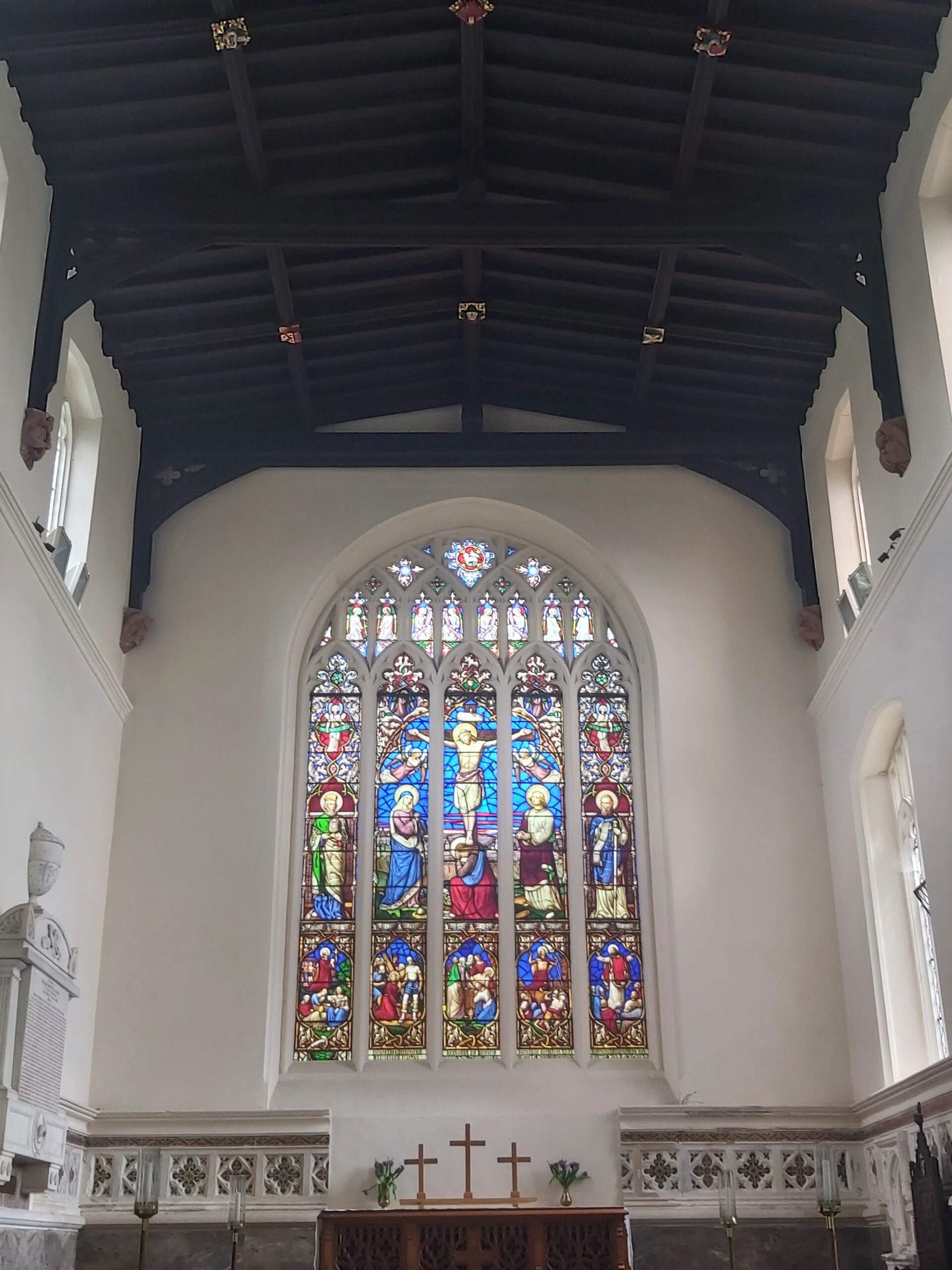 A large stained glass window depicting Christ on the cross in St Mary's Church, Ware, England