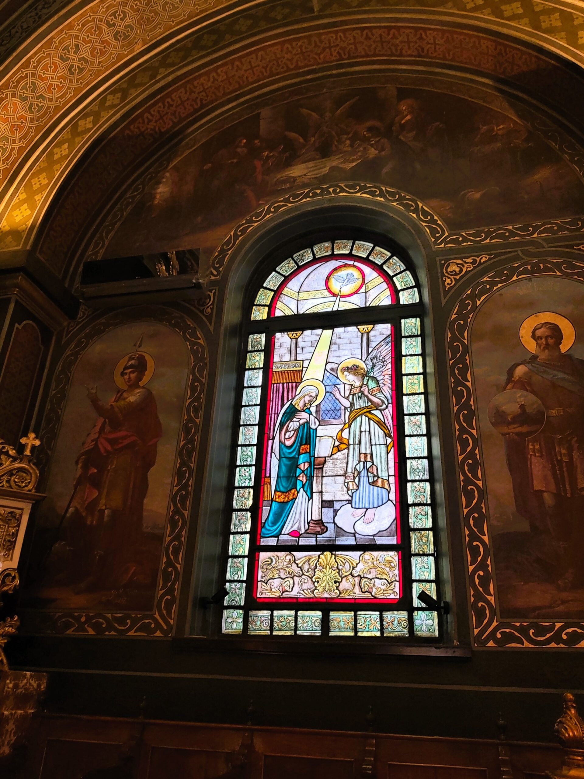 A stained glass window and paintings in a church in București, Romania