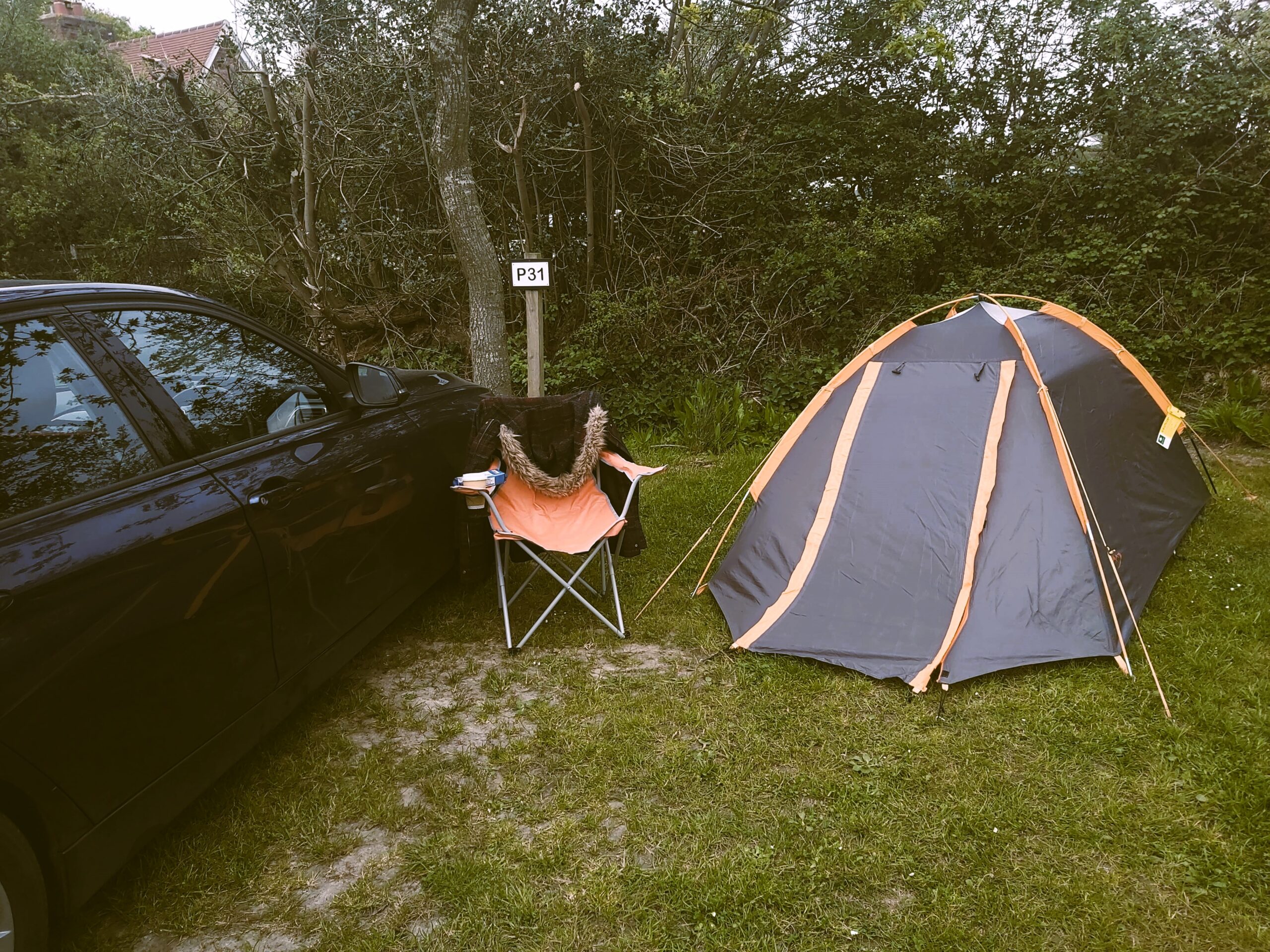 Car, tent and chair at a pitch on Norden Farm campsite, Dorset, England