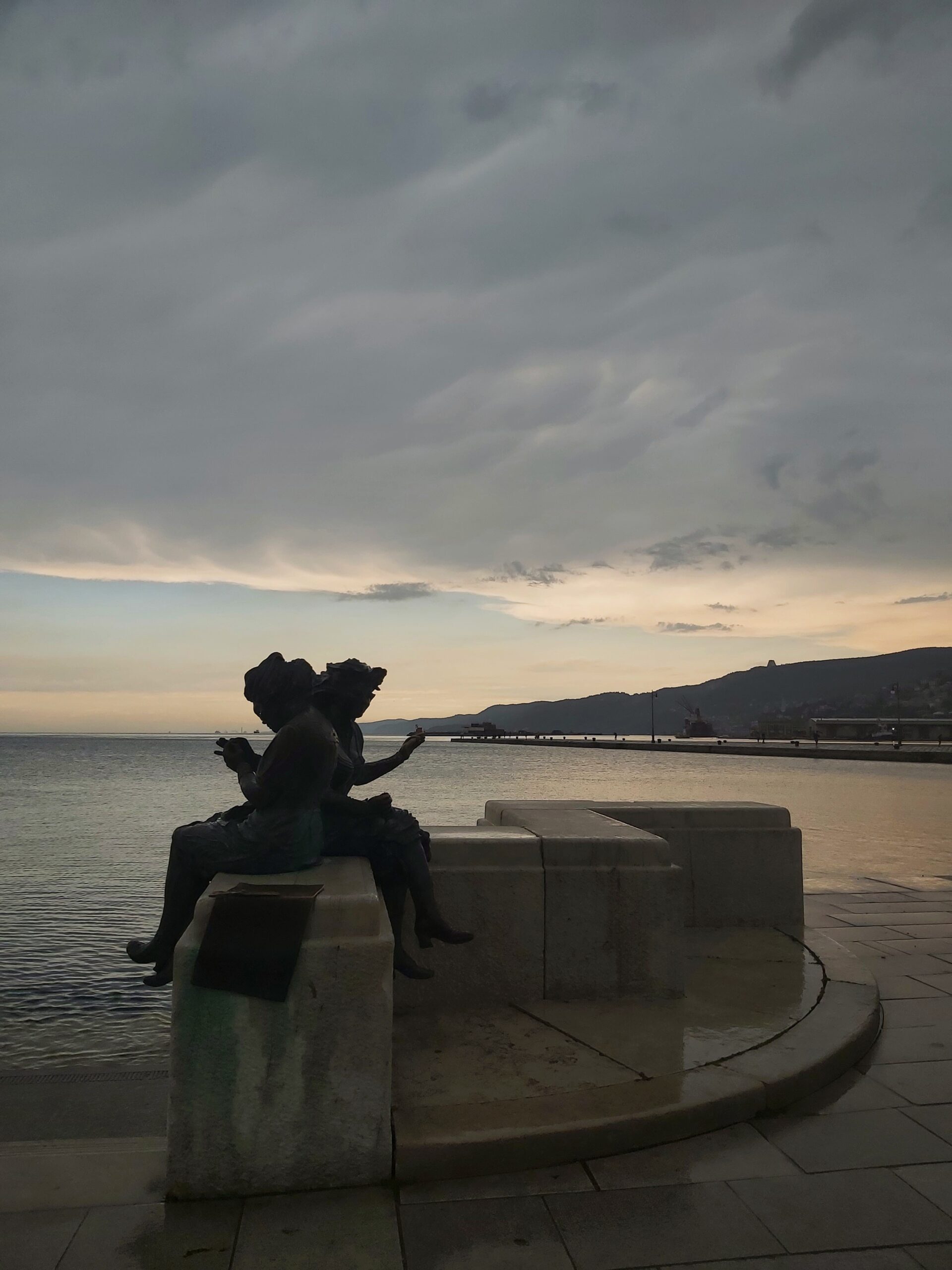 A statue of two women sewing, "Le Ragazze di Trieste", by the harbour in Trieste, Italy