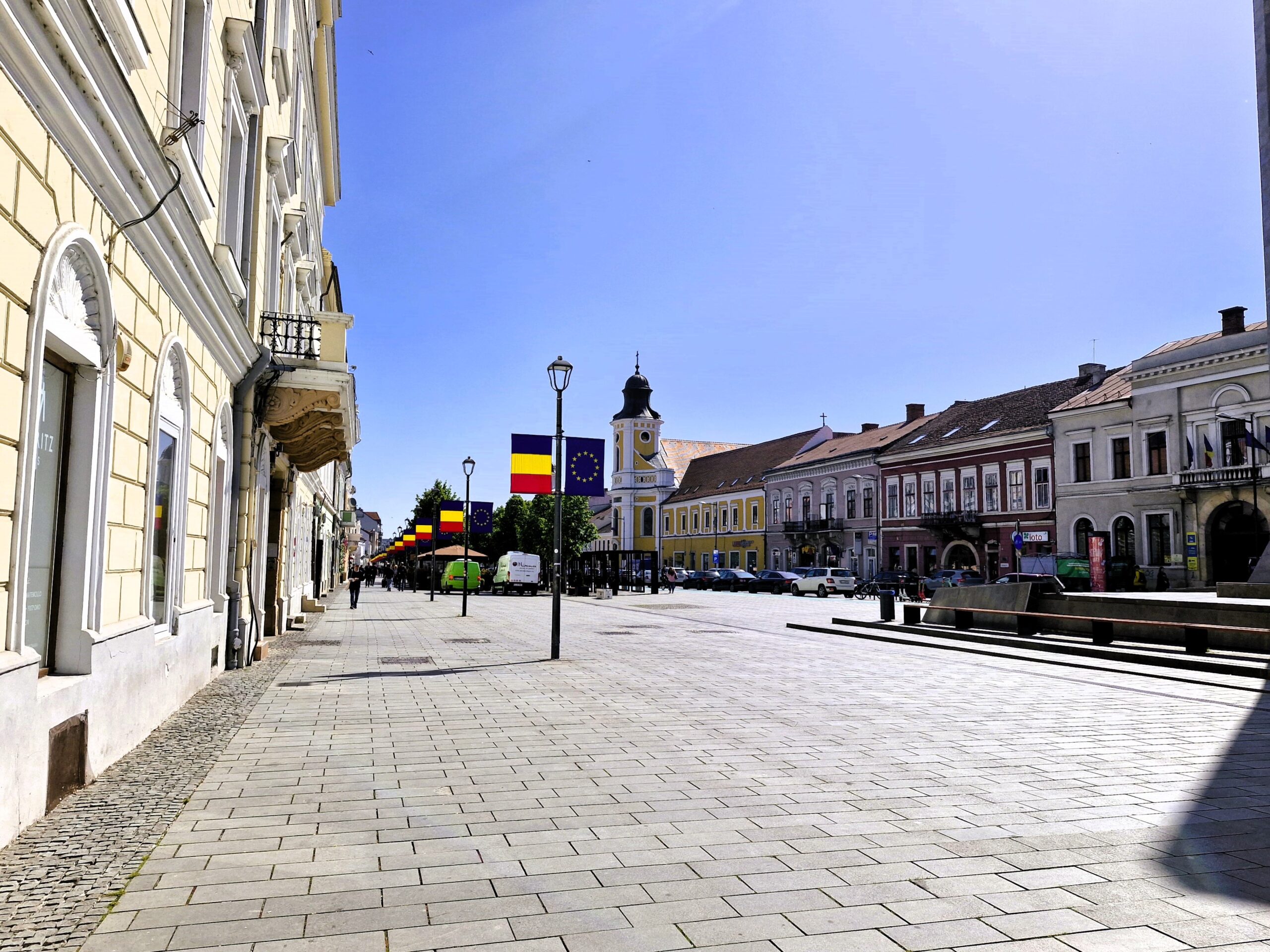 A clean street in Cluj with Romanian flags along it