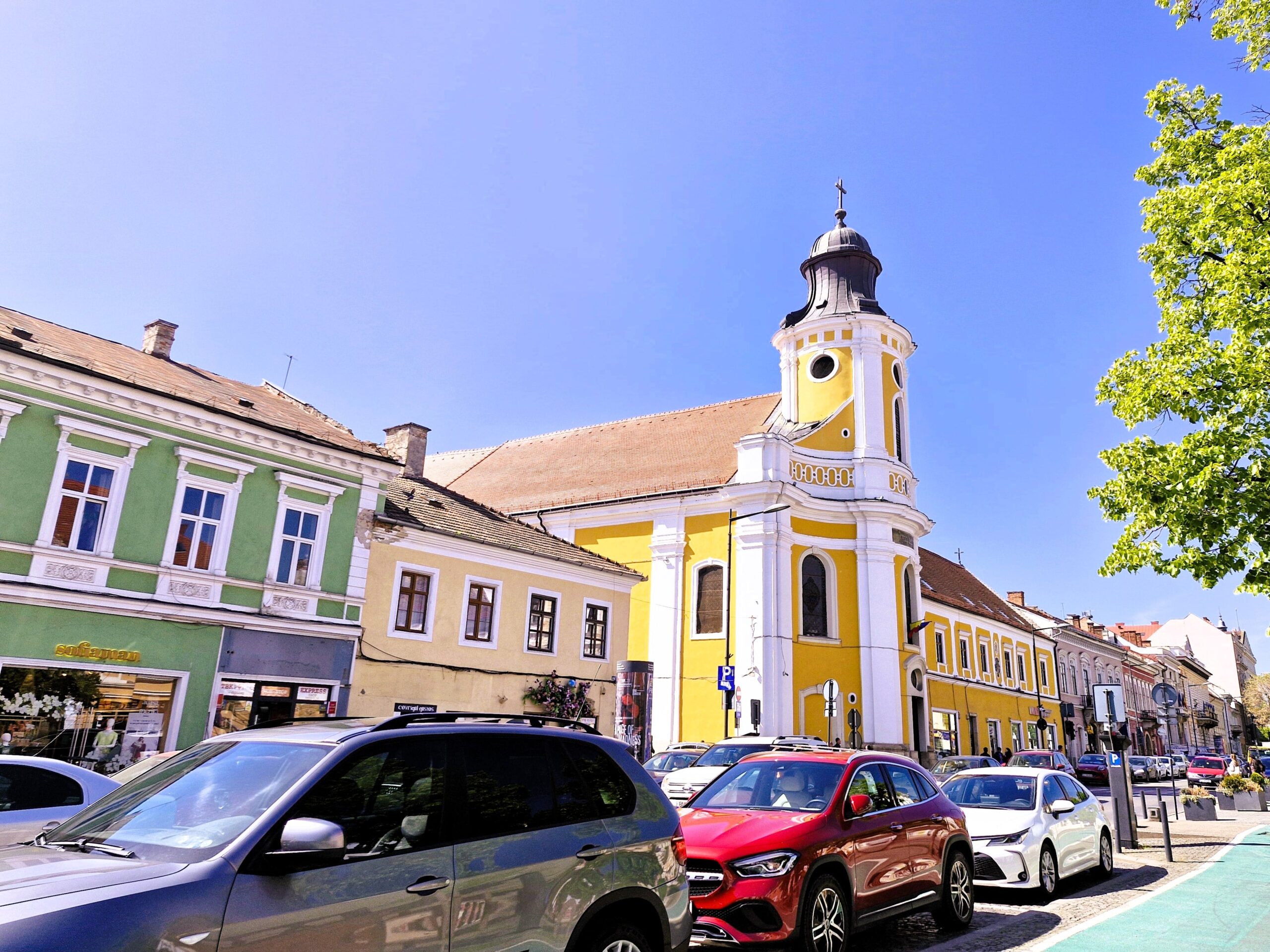 A bright yellow spire stands tall in a street in Cluj-Napoca, Romania