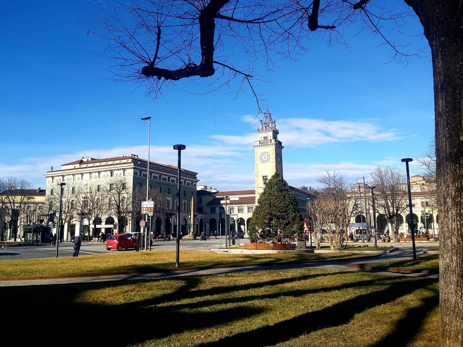 A pretty view of the clocktower against a blue sky in Città Bassa, looking across the grass.